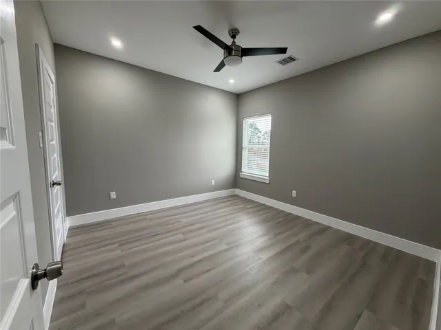 an empty room with wooden floor and windows