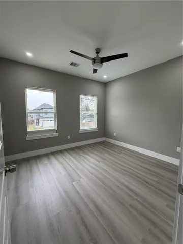 an empty room with wooden floor and windows