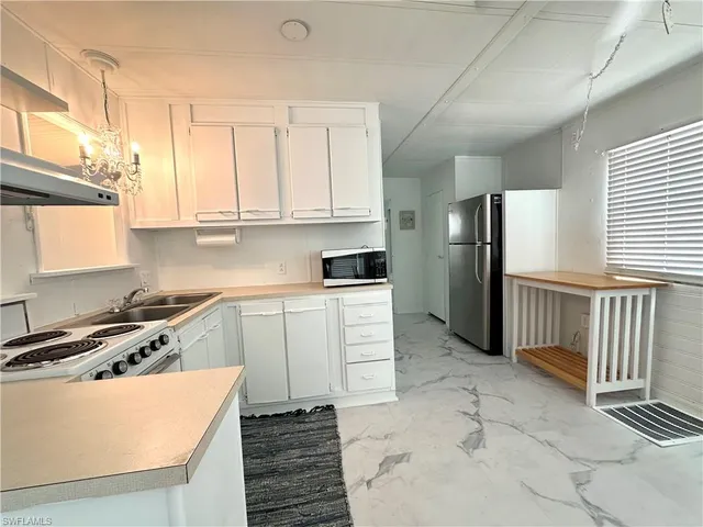 a kitchen with stainless steel appliances granite countertop a refrigerator a stove and a sink