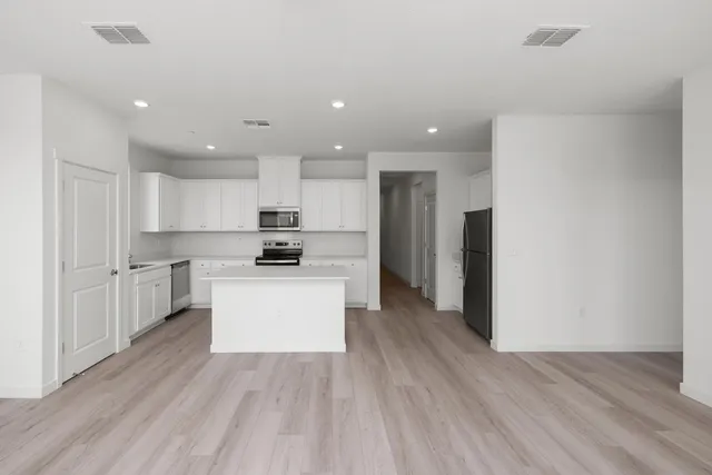 a large kitchen with white cabinets and stainless steel appliances