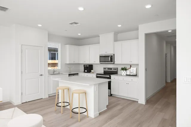 a kitchen with a refrigerator a stove cabinets and wooden floor