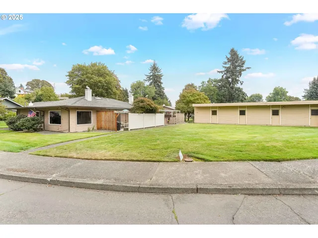 a view of house with a big yard and potted plants