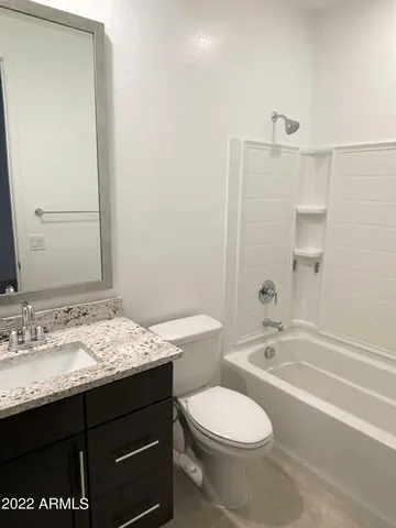 a bathroom with a granite countertop sink toilet a large mirror a bathtub and shower