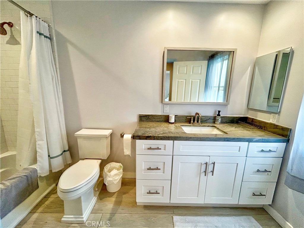 258 West Escalones, Unit 6R San Clemente, CA 92672 - Photo 34 of 37 a bathroom with a granite countertop toilet sink and mirror