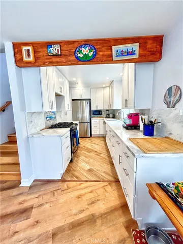 a large white kitchen with stainless steel appliances kitchen island a stove a sink and a refrigerator