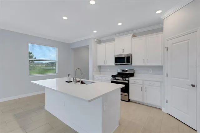 a kitchen with stainless steel appliances a sink a stove a microwave a refrigerator a window