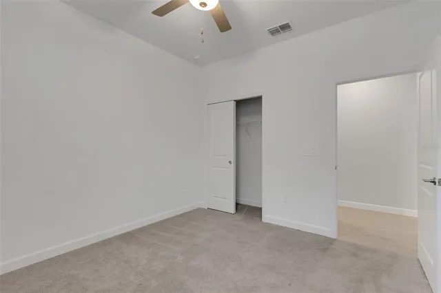 an empty room with a ceiling fan and a window