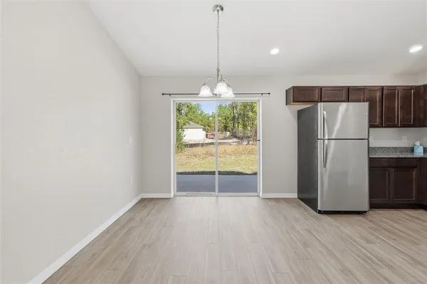 a view of a kitchen with a refrigerator wooden floor and a window
