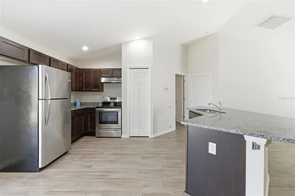 a kitchen with stainless steel appliances granite countertop a refrigerator a stove and a sink