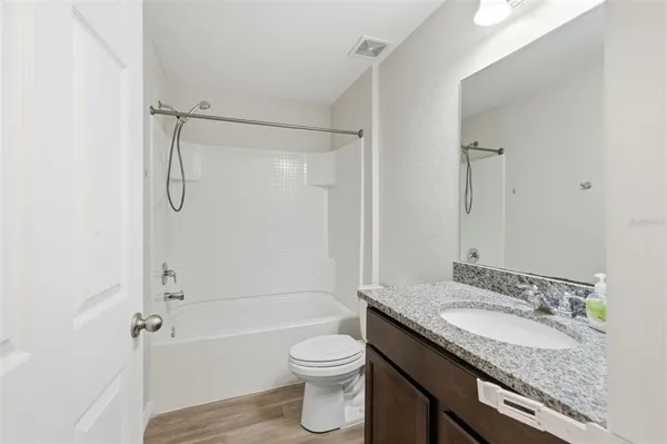 a bathroom with a granite countertop sink toilet and shower