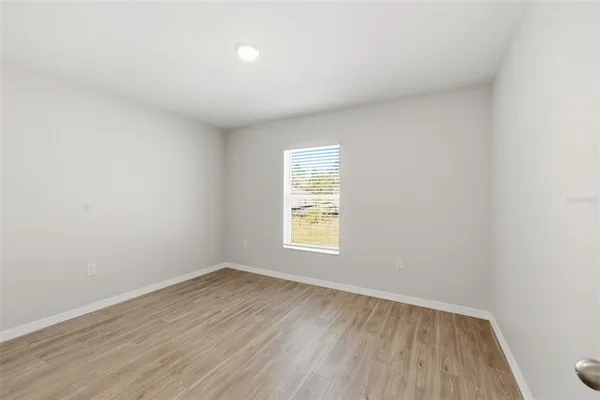 an empty room with wooden floor and window