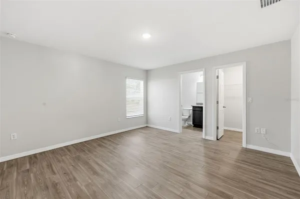 a view of an empty room with wooden floor and window