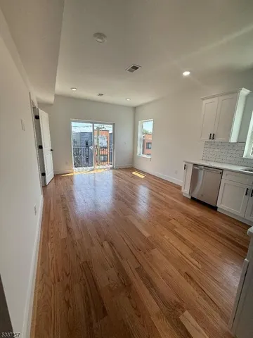 a view of empty room with wooden floor and window