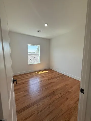 an empty room with wooden floor and window