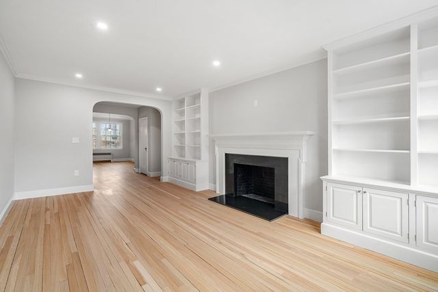 a view of an empty room with wooden floor fireplace and a window