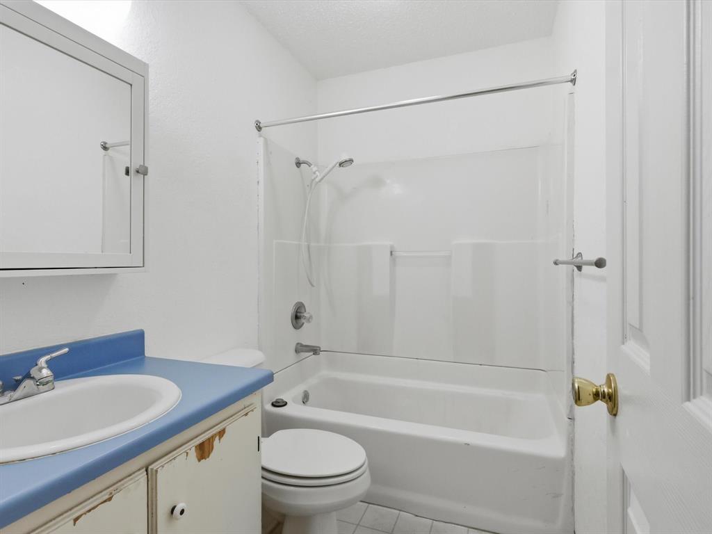 701 College Street Celeste, TX 75423 - Photo 20 of 29 a bathroom with a granite countertop toilet a sink and a bathtub