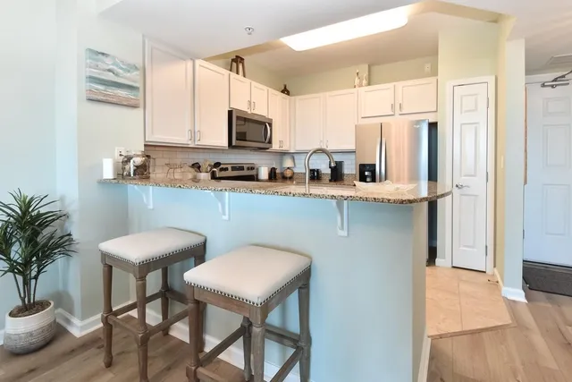 a kitchen with stainless steel appliances granite countertop a table chairs microwave and sink