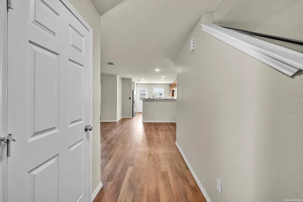 a view of a hallway with wooden floor and a bathroom