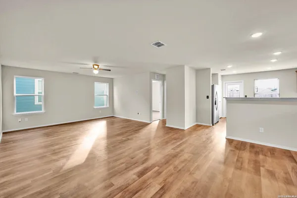 a view of an empty room with window and wooden floor