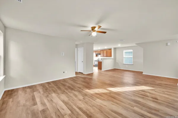 a view of empty room with wooden floor and fan
