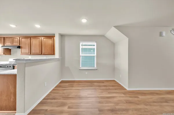 a view of empty room with wooden floor and fan