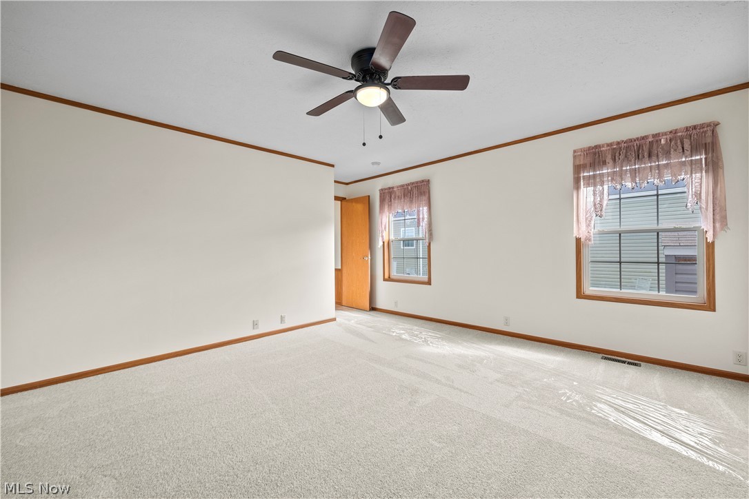 35157 Center Ridge Road, Unit 92 North Ridgeville, OH 44039 - Photo 14 of 40 Plush wall-to-wall carpeting, ceiling fan with integrated lighting, two windows with wood-trim framing, and a wooden door