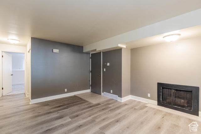 167 East 100 North, Unit B Logan, UT 84321 - Photo 9 of 18 Unfurnished living room featuring light wood-style flooring and a fireplace with flush hearth