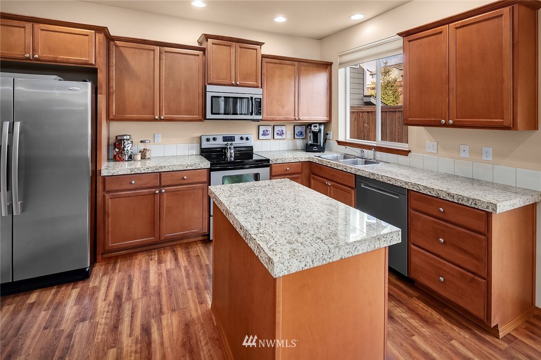 23019 42nd Drive Southeast Bothell, WA 98021 - Photo 5 of 19 a kitchen with stainless steel appliances granite countertop white cabinets a refrigerator a sink a stove a microwave and wooden floors