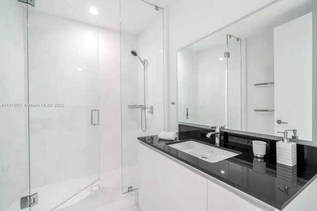 a bathroom with a granite countertop sink a mirror and shower