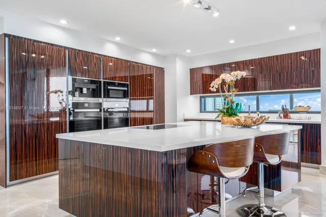 a kitchen with stainless steel appliances kitchen island granite countertop a refrigerator a stove and a sink with wooden cabinets