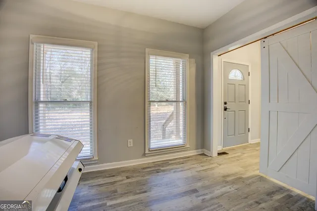 a view of an empty room with wooden floor and a window
