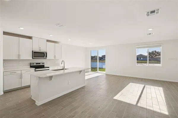 a kitchen with stainless steel appliances granite countertop a stove top oven a sink dishwasher and a refrigerator with wooden floor