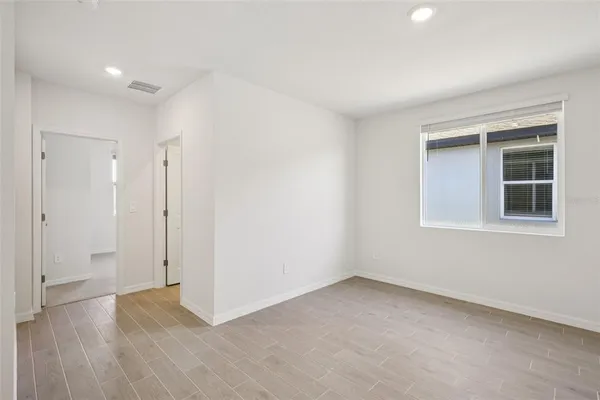 a view of an empty room with wooden floor and a window