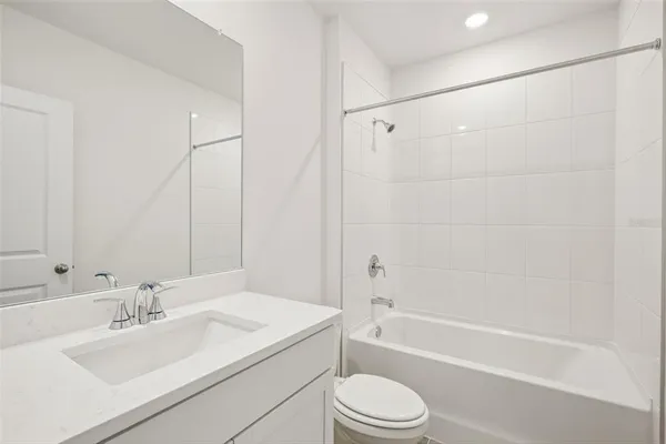 a bathroom with a bathtub shower sink vanity mirror and toilet