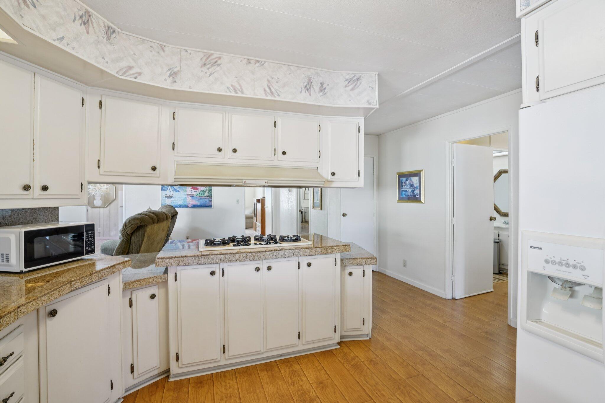 74584 Nevada Circle East Palm Desert, CA 92260 - Photo 19 of 46 a kitchen with stainless steel appliances granite countertop a sink and a white cabinets with wooden floor
