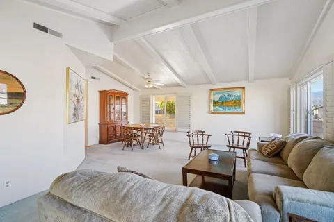 a living room with furniture kitchen view and a window