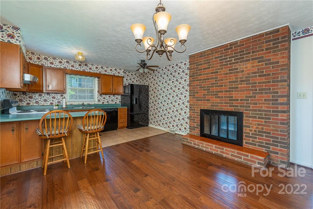 62 Round Top Road Asheville, NC 28803 - Photo 9 of 46 a dining room with furniture wooden floor a fireplace and a chandelier