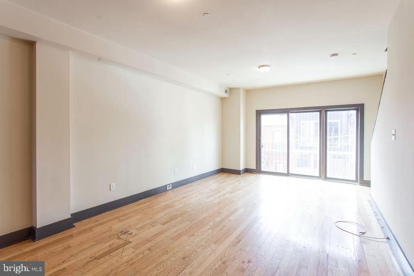1826 West Norris Street, Unit 2 Philadelphia, PA 19121 - Photo 3 of 23 a view of an empty room with wooden floor and a window