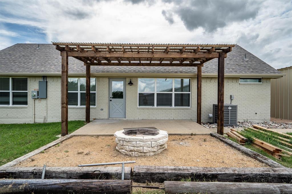 13132 Highway 78 Blue Ridge, TX 75424 - Photo 21 of 35 Rear patio featuring a pergola, concrete-paved area, and a stone-clad fire pit