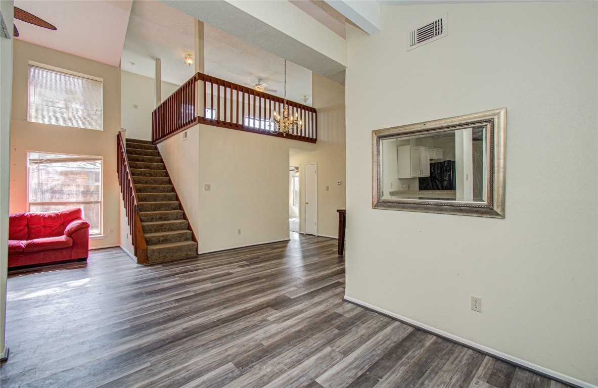 4911 Tealgate Drive Spring, TX 77373 - Photo 15 of 41 This spacious living area features high ceilings, a loft-style upper level, and a neutral color palette. The open layout includes a staircase leading upstairs, laminate wood flooring, and large windows that allow natural light to flood the space. A decorative mirror and a cozy seating area enhance the room's appeal.
