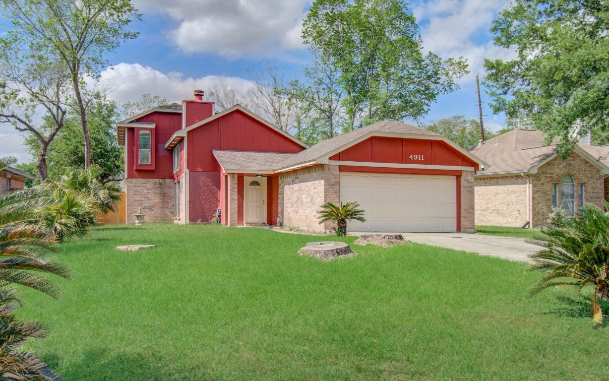 4911 Tealgate Drive Spring, TX 77373 - Photo 2 of 41 This charming home features a bold red exterior with brick accents. It has a well-maintained lawn, a two-car garage, and mature trees, offering great curb appeal.