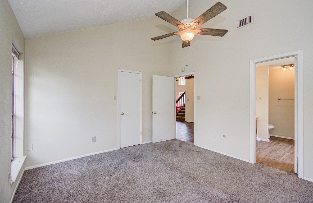 4911 Tealgate Drive Spring, TX 77373 - Photo 23 of 41 This room features neutral-colored walls and carpet, a ceiling fan with light, and large windows for natural light. It connects to a wood-floored hallway and an adjacent bathroom, creating a versatile living space.