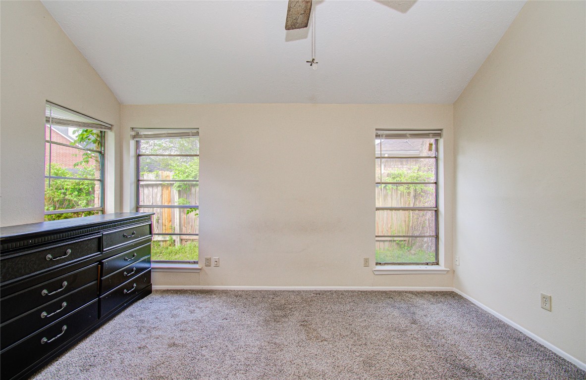 4911 Tealgate Drive Spring, TX 77373 - Photo 24 of 41 This room features neutral walls, carpeted flooring, and two large windows offering natural light. A dark wood dresser is placed against one wall, and a ceiling fan is installed above, providing comfort and style.