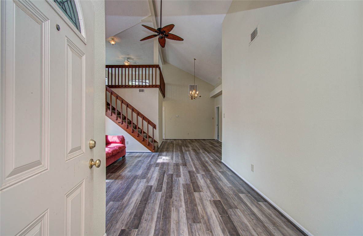 4911 Tealgate Drive Spring, TX 77373 - Photo 6 of 41 Welcome to a spacious, open-concept living area featuring high ceilings, a modern chandelier, and wood-style flooring. The room includes a loft area accessed by a staircase, adding character and functionality to the space.