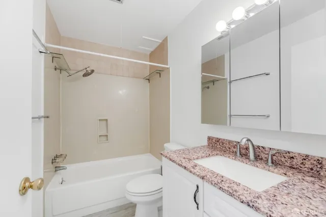a bathroom with a granite countertop sink mirror toilet and bathtub