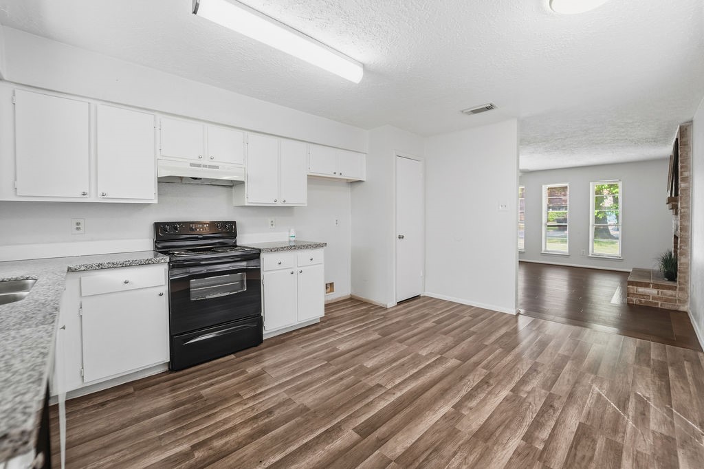 4542 Algernon Drive Spring, TX 77373 - Photo 4 of 19 a kitchen with granite countertop a stove a sink and white cabinets with wooden floor