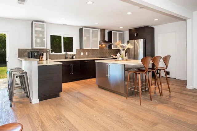 a kitchen with stainless steel appliances kitchen island granite countertop a table chairs and a refrigerator