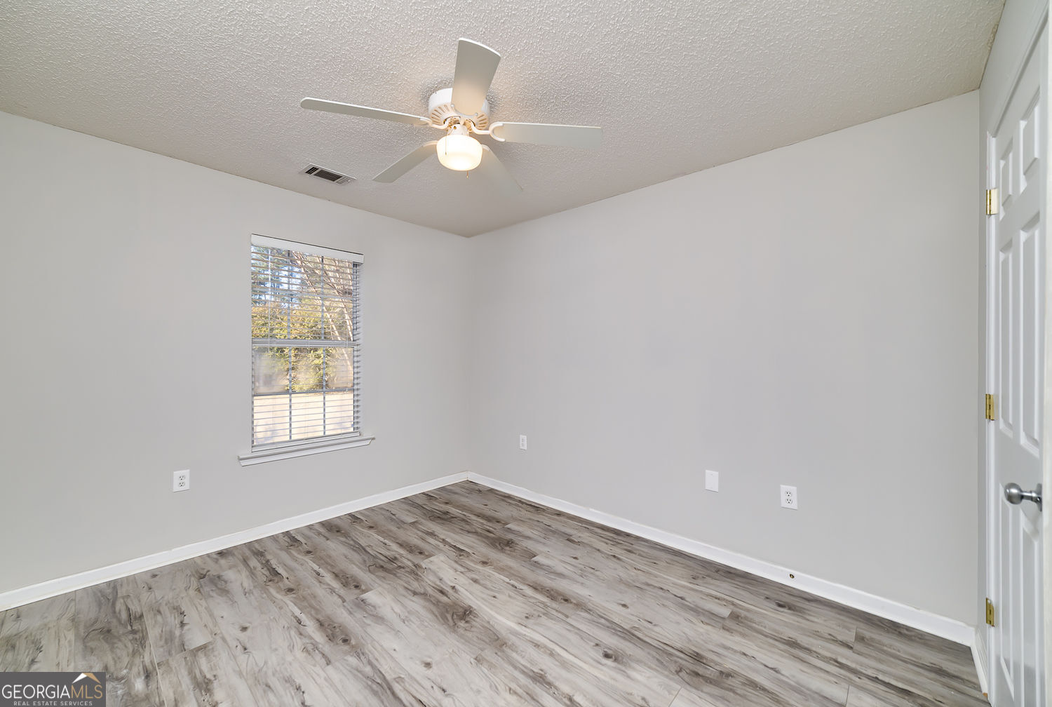 524 Leguin Mill Road Locust Grove, GA 30248 - Photo 36 of 44 an empty room with wooden floor fan and windows