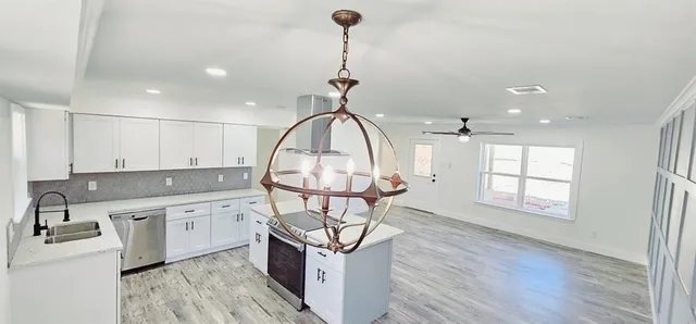 a kitchen with stainless steel appliances granite countertop a sink a window and wooden floors