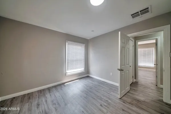 a view of an empty room with wooden floor and a window